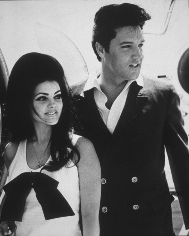 Elvis Presley und Priscilla stehen zusammen vor einem Flugzeug.