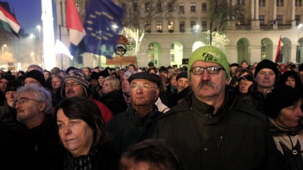 Eine Menschenmenge demonstriert mit ungarischen und EU-Flaggen im Hintergrund.