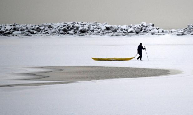 Ein Mann spaziert auf dem zugefrorenen Meer, inmitten von verschneitem Wetter im Süden Helsinkis, Finnland, 2. Januar 2024.