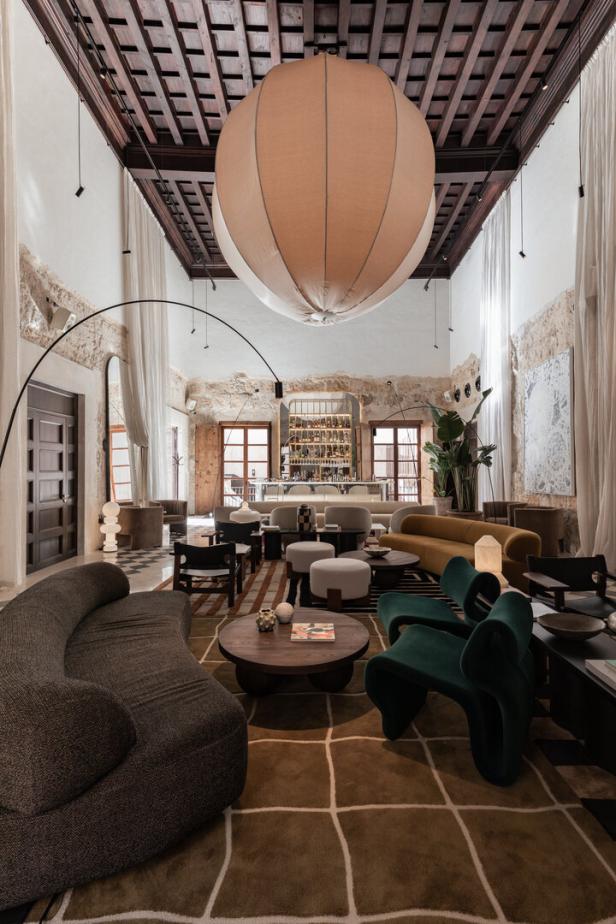 Ein weitläufiger Hotellobbybereich mit verschiedenen Sitzgelegenheiten und einer Bar im Hintergrund.
