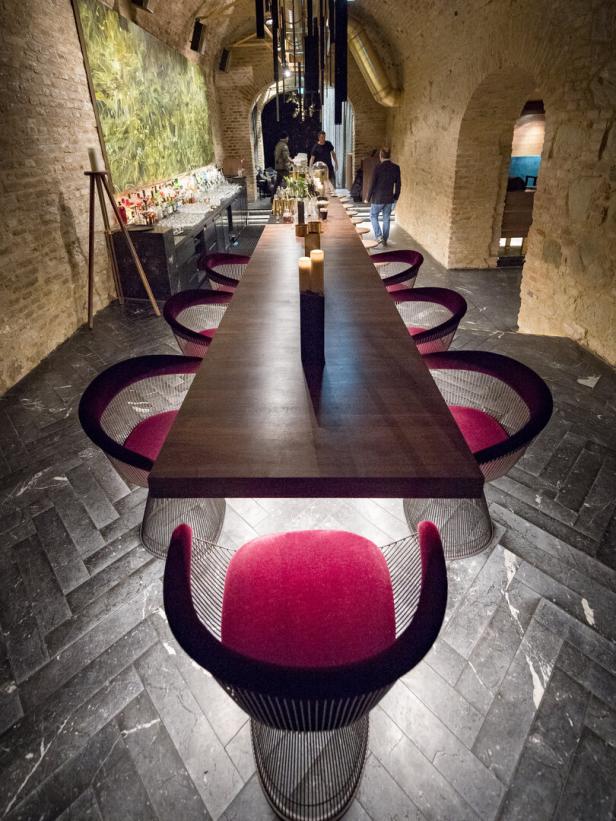 Ein langer Tisch mit roten Stühlen in einem Restaurant mit Steinwänden.