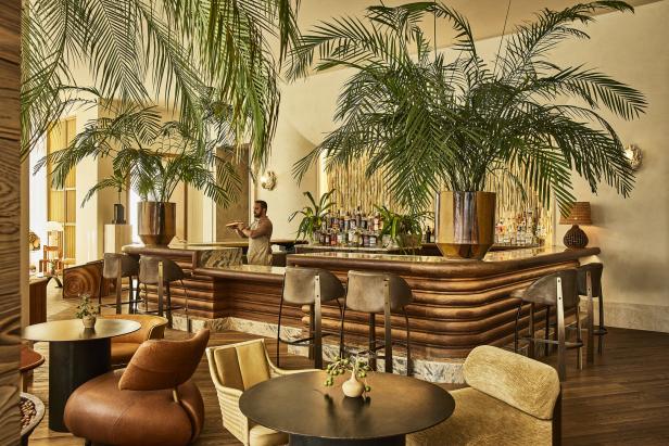 Eine Bar mit Holzelementen und tropischen Pflanzen, an der ein Barkeeper steht.