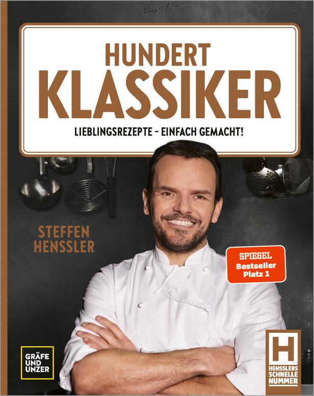 Steffen Henssler vor dem Cover seines Buches „Hundert Klassiker“.