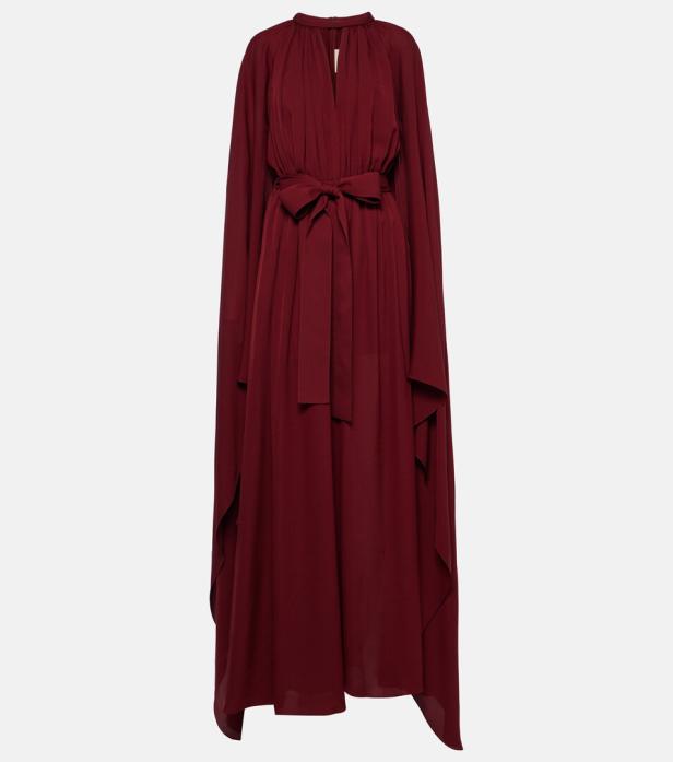Ein langes, weinrotes Kleid mit einem Gürtel und einem Cape-artigen Überwurf.