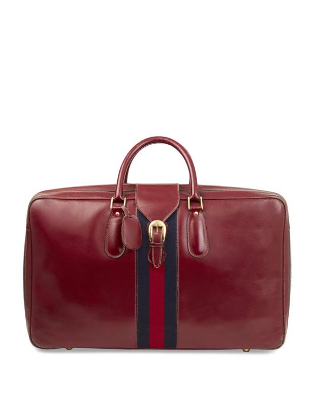 Eine rote Reisetasche aus Leder mit einem Streifen in den Farben Rot und Dunkelblau in der Mitte.