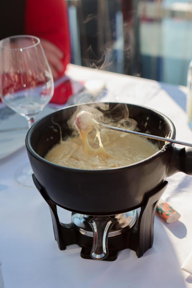 Ein Käsefondue wird auf einem Tisch mit einem Glas Wein serviert.
