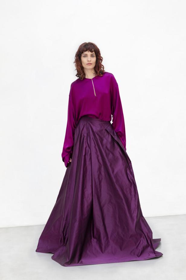 Eine Frau trägt eine violette Bluse und einen langen, weiten Rock in Lila.