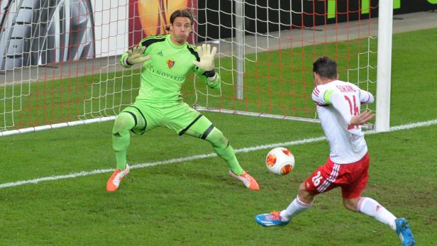 Ein Fußballspieler schießt auf das Tor, während der Torwart versucht, den Ball abzuwehren.