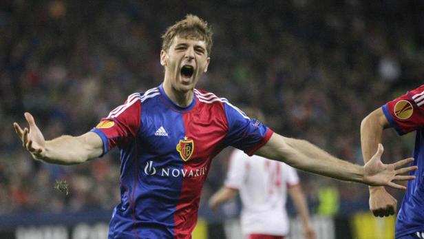 Ein jubelnder Fußballspieler im rot-blauen Trikot des FC Basel mit ausgestreckten Armen.