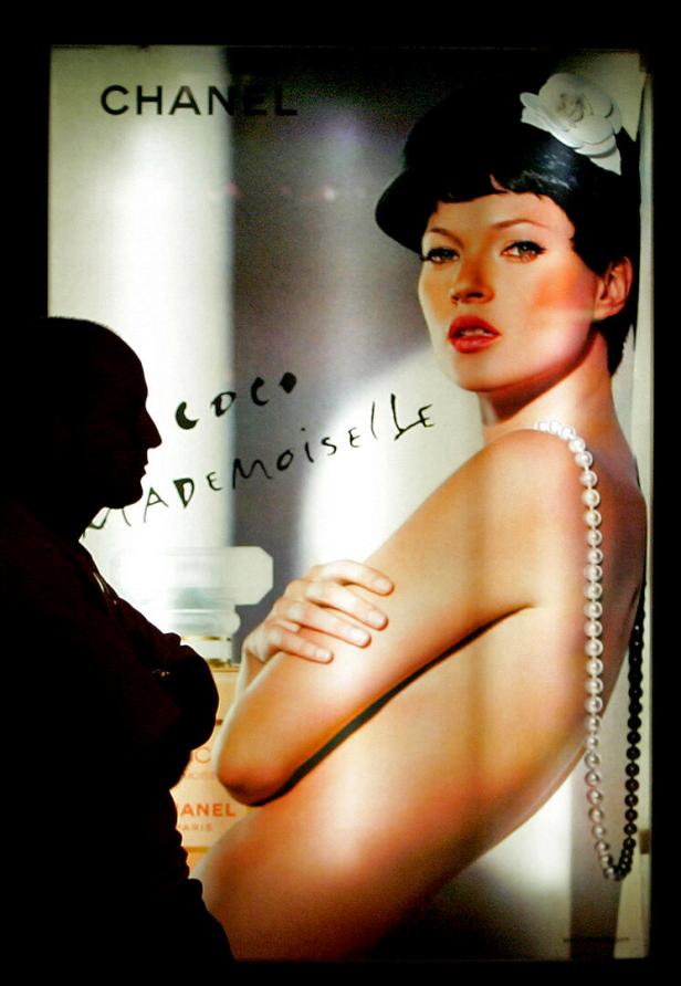 Ein Mann steht vor einem Chanel-Werbeplakat mit Kate Moss für „Coco Mademoiselle“.