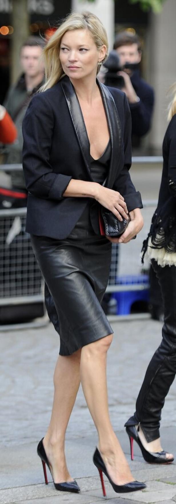 Kate Moss trägt einen schwarzen Blazer und einen Lederrock.