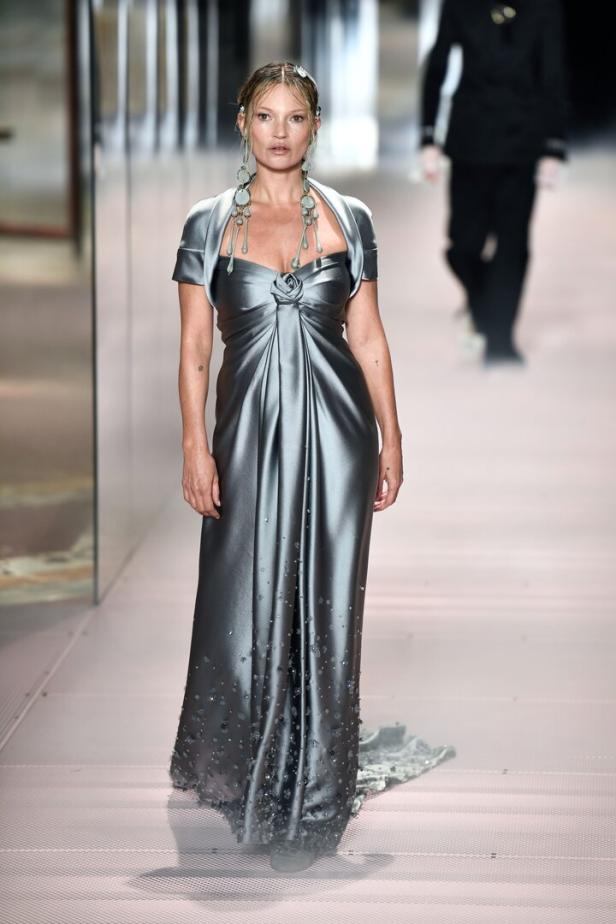 Kate Moss in einem grauen Abendkleid auf einem Laufsteg.