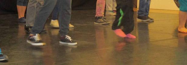 Mehrere Personen stehen barfuß oder mit Schuhen auf einem glänzenden Boden.