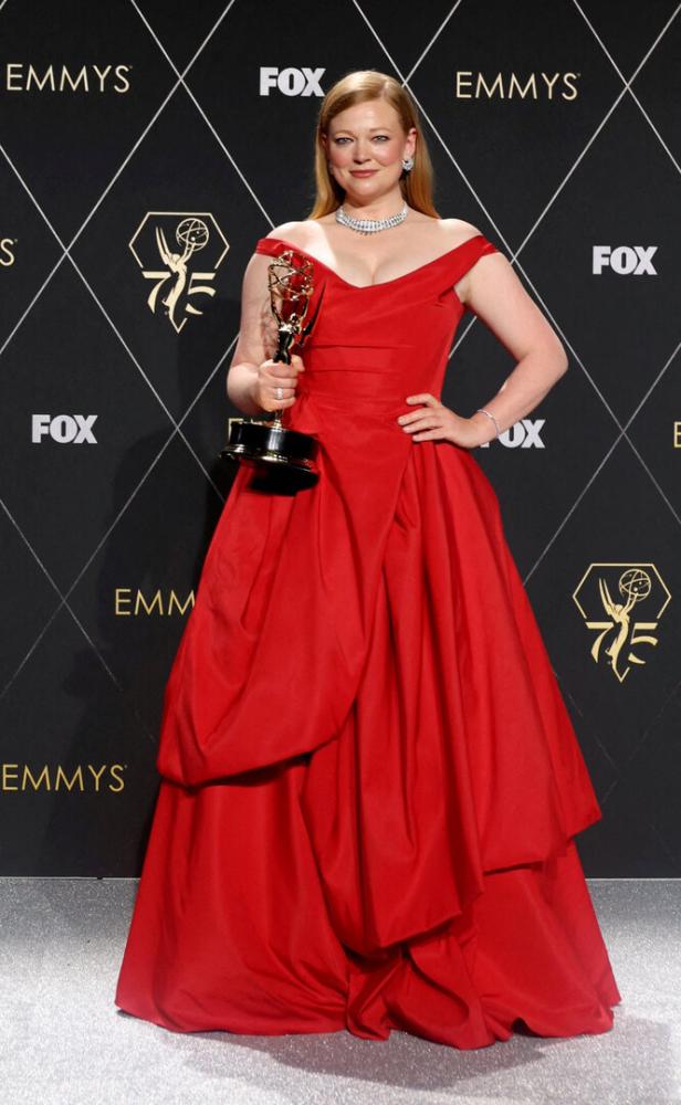 Sarah Snook in einem roten Kleid mit einer Emmy-Trophäe in der Hand.