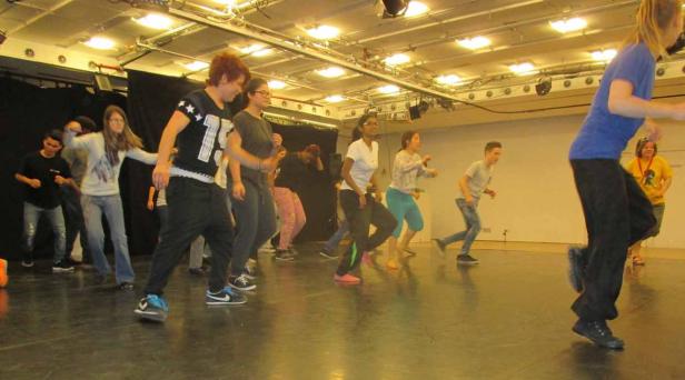 Eine Gruppe von Teenagern tanzt in einem hell erleuchteten Raum.