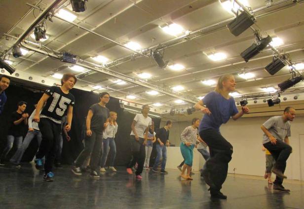 Eine Gruppe von Menschen tanzt in einem hell erleuchteten Studio.