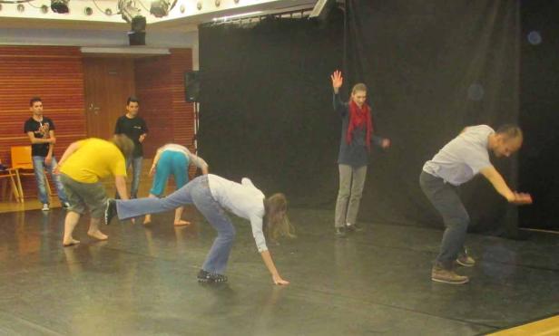 Eine Gruppe von Menschen übt eine Performance auf einer Bühne.