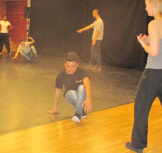 Eine Gruppe von Tänzern übt Breakdance auf einer Bühne.