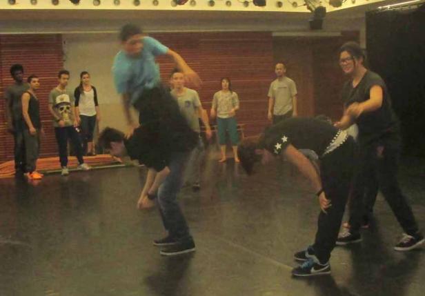 Eine Gruppe von Leuten übt eine akrobatische Tanzperformance in einem Studio.