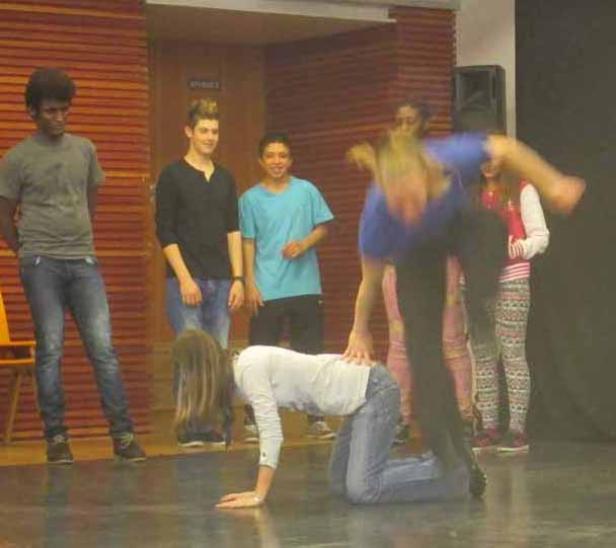 Eine Gruppe von Jugendlichen führt eine akrobatische Übung auf einer Bühne auf.