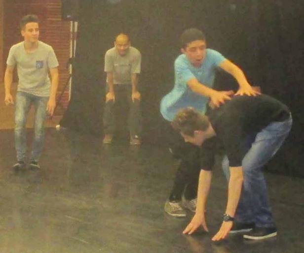 Eine Gruppe junger Männer scheint auf einer Bühne zu proben oder zu spielen.