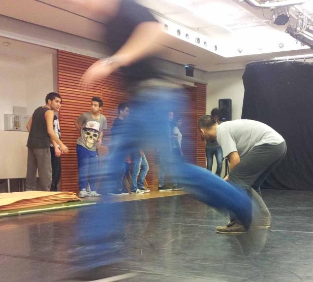 Eine Gruppe junger Männer probt eine Tanzperformance auf einer Bühne.