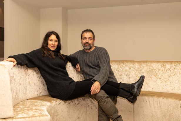 Eine Frau und ein Mann sitzen auf einem goldenen Sofa.