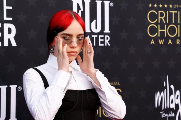 Billie Eilish bei den Critics Choice Awards mit rotem Haar und runder Brille.