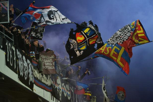 Fußballfans schwenken Fahnen und Banner im Stadion.