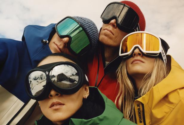 Eine Gruppe von Personen mit Skibrillen und Winterkleidung blickt in die Kamera.