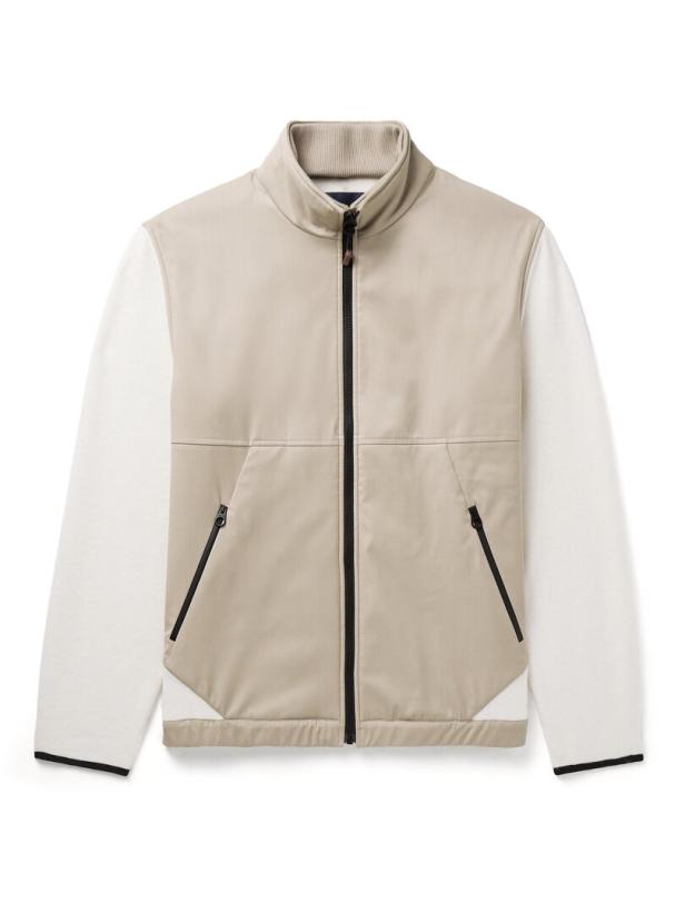 Eine beige Jacke mit weißen Ärmeln und einem schwarzen Reißverschluss.
