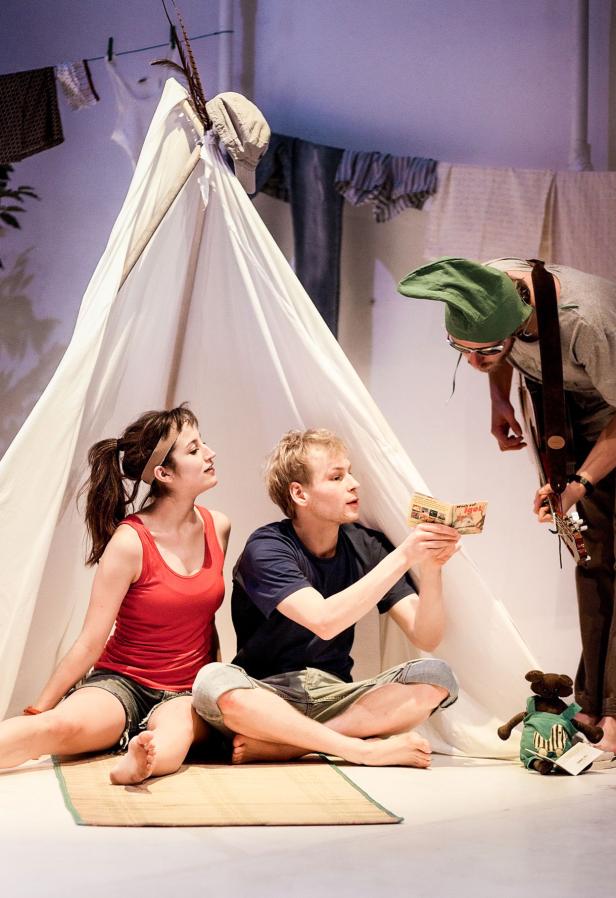 Drei Personen in einem Zelt, eine liest ein Buch, eine hört zu, eine spielt Gitarre.