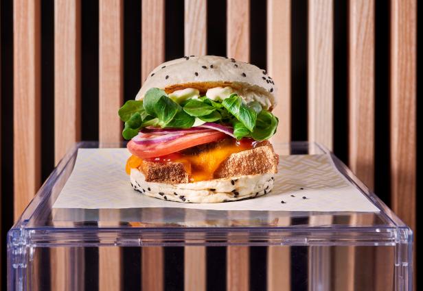 Ein vegetarischer Burger mit Salat, Tomate und Zwiebel auf einem Tisch.