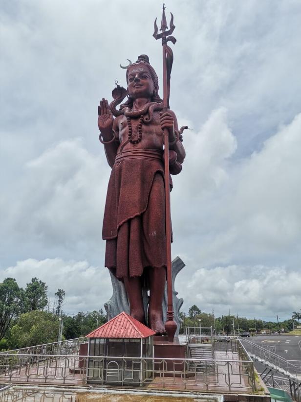 Eine große Statue von Shiva unter einem bewölkten Himmel.