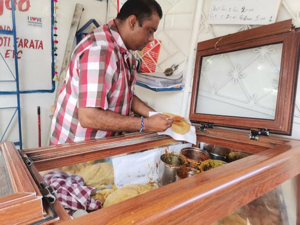 Ein Mann bereitet an einem Stand Dhol Puri und Roti zu.