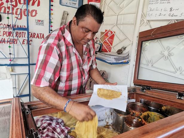 Ein Mann bereitet an einem Stand Dholl Puri und Roti zu.
