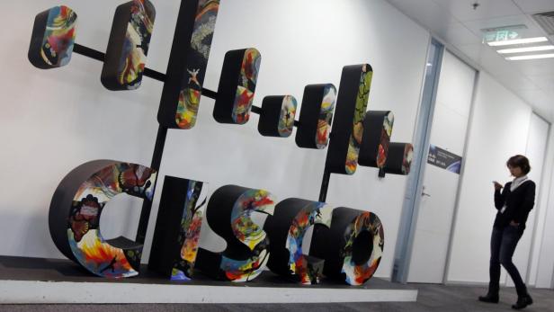 Eine Frau steht in einem Flur neben einer großen, bunten „Cisco“-Skulptur.