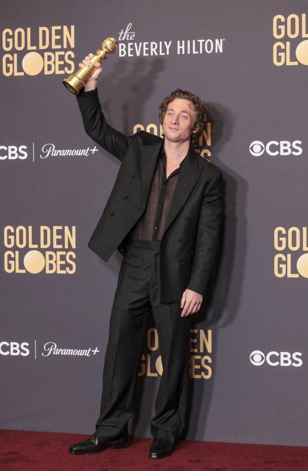 Jeremy Allen White hält seinen Golden Globe Award hoch.