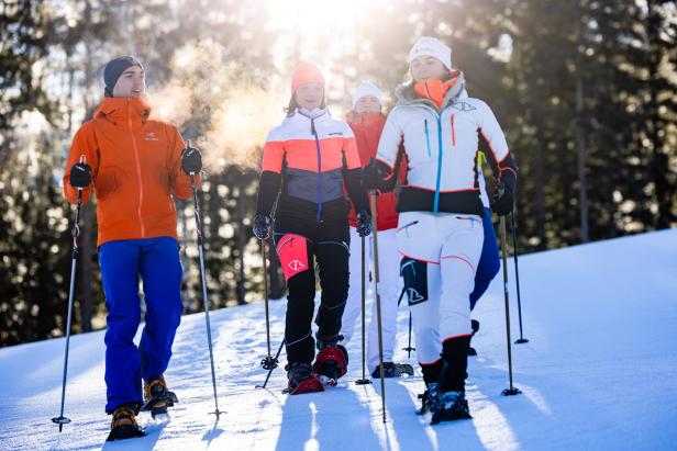 Eine Gruppe von Personen geht mit Schneeschuhen durch eine verschneite Landschaft.