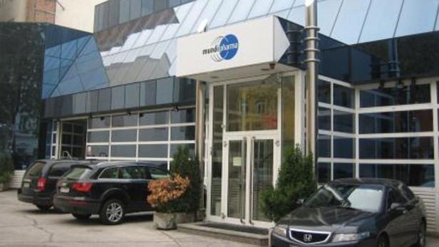 Das Mundipharma-Gebäude mit geparkten Autos davor.