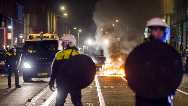 xyz Niederländische Polizisten stehen vor einem brennenden Barrikade auf einer Straße.