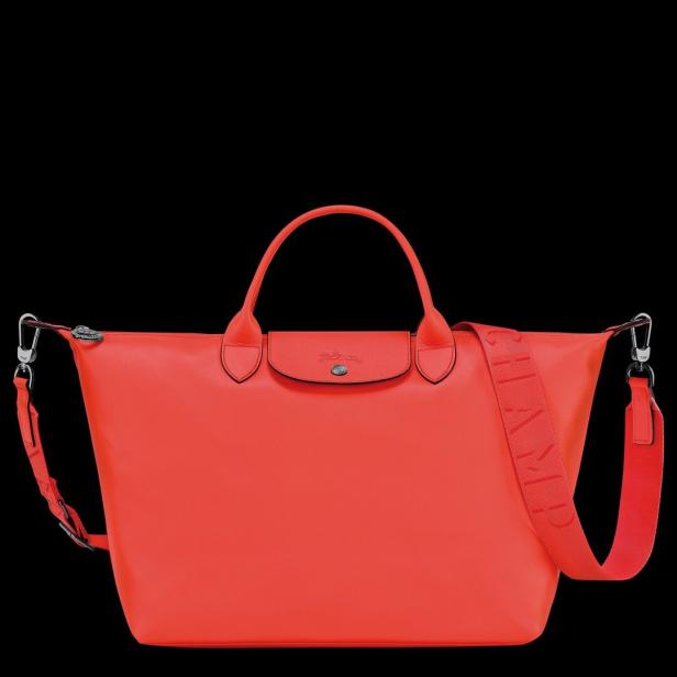 Eine rote Longchamp Handtasche mit Schultergurt vor schwarzem Hintergrund.