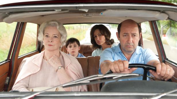 Eine Familie sitzt ernst in einem älteren Auto.