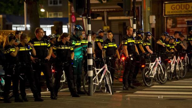 xyz Eine Gruppe niederländischer Polizisten steht mit ihren Fahrrädern auf einem Zebrastreifen.
