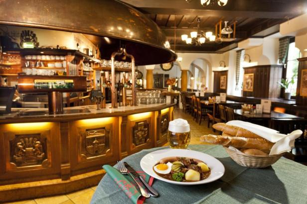 Im Gösser Bräu steht ein Teller mit deftigem Essen und ein Bier bereit.