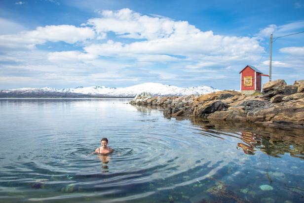 Eine Frau schwimmt in einem See mit schneebedeckten Bergen im Hintergrund.
