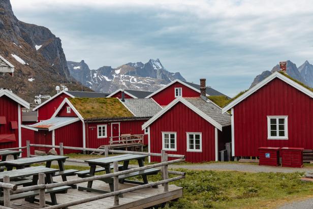 Rote Holzhäuser mit Grasdächern in einer norwegischen Landschaft.