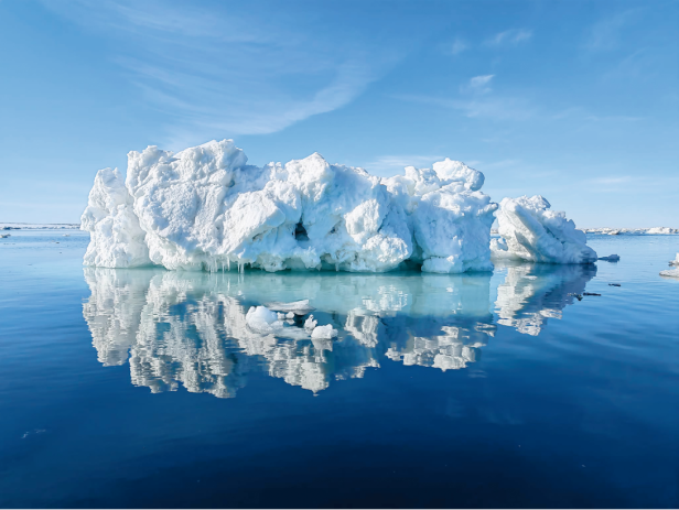 Ein großer Eisberg spiegelt sich im ruhigen, blauen Wasser.