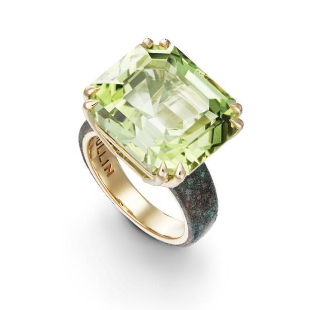 Ein Ring mit einem großen, hellgrünen Edelstein auf einem goldenen Band.