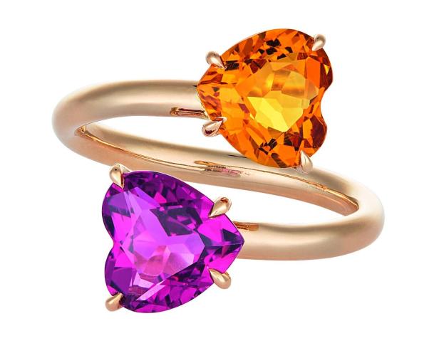Ein goldener Ring mit zwei herzförmigen Steinen in Orange und Lila.